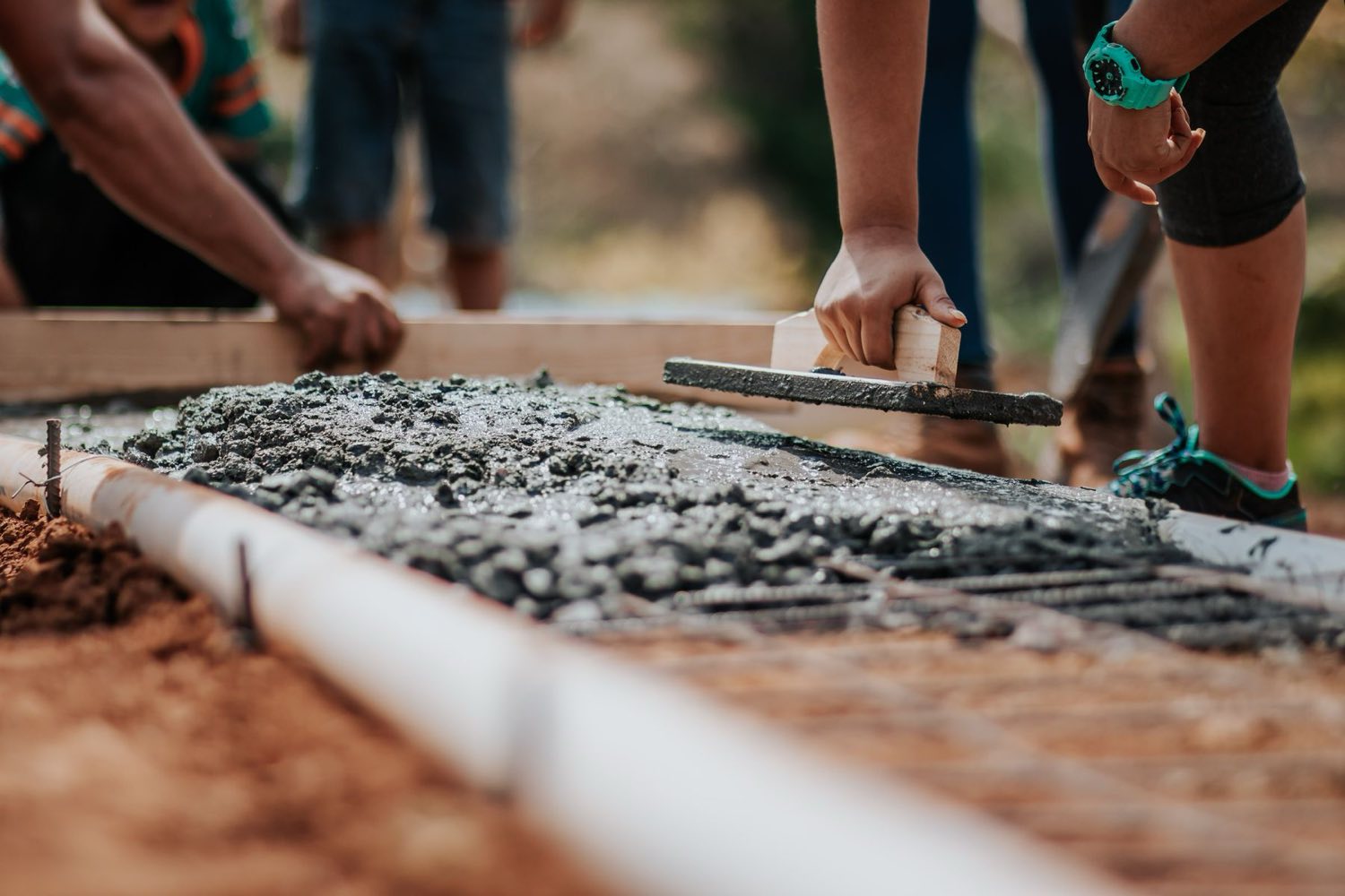 Hand float smoothing fresh concrete at the edge of a formed slab